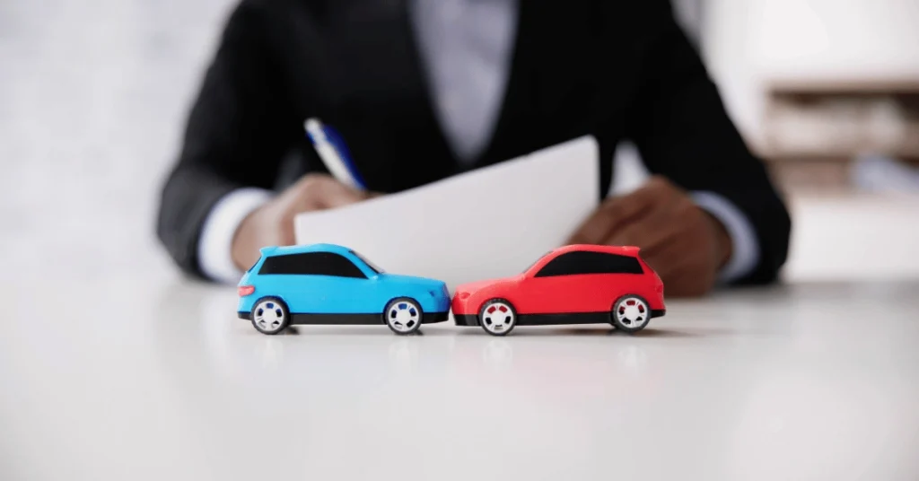 Two model cars representing a collision while an attorney reviews documents, illustrating a Portland car accident claim.