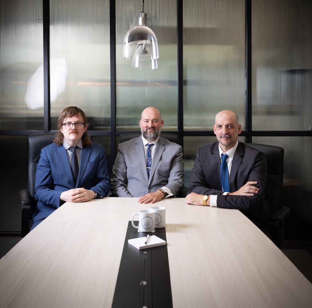 Collin Armfield, Spencer Aldrich, and Zachary Brunot seated together at the conference table in the Aldrich & Brunot office